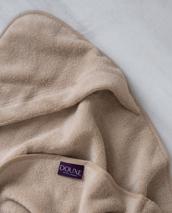 badcape baby in latte, detail shot van capuchon en DOUXE logo met marmeren achtergrond