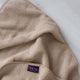 badcape baby in latte, detail shot van capuchon en DOUXE logo met marmeren achtergrond