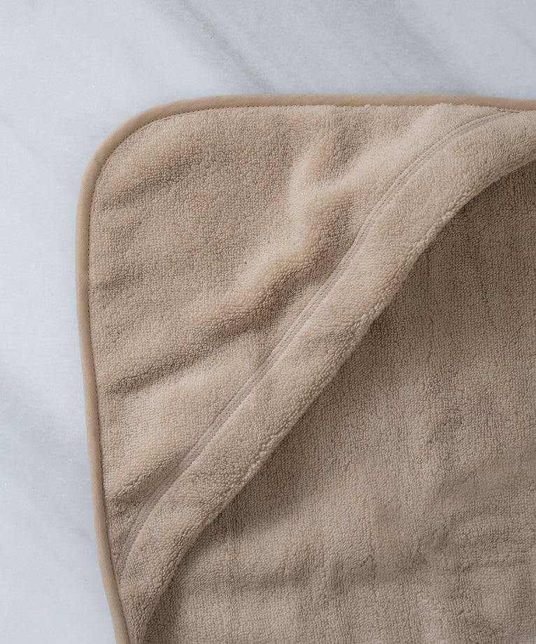 baby badcape in latte, detail shot van capuchon met marmeren achtergrond