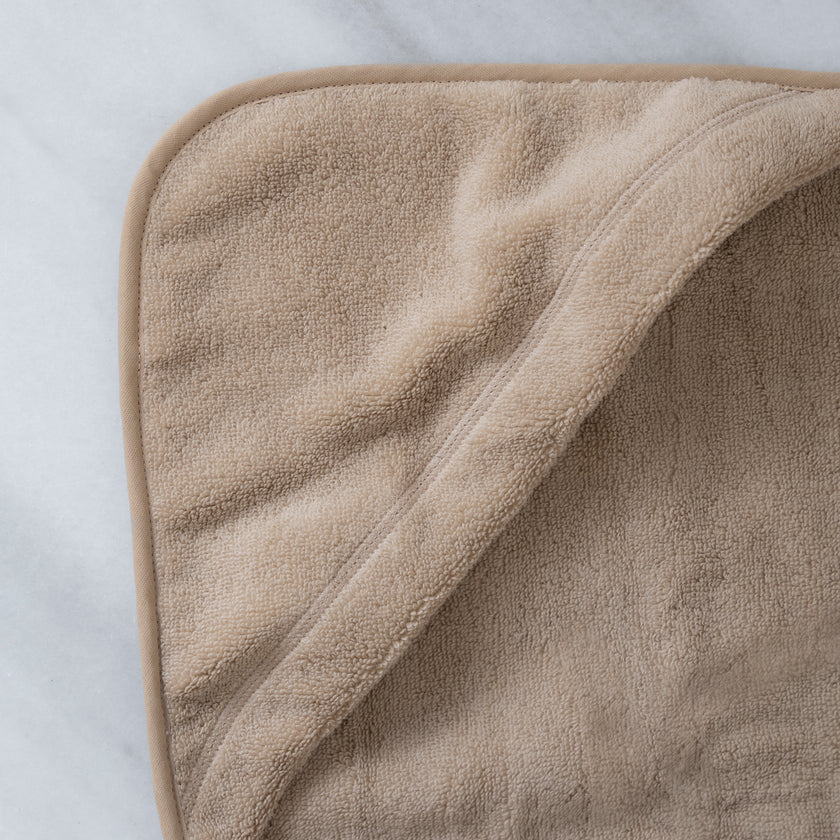 baby badcape in latte, detail shot van capuchon met marmeren achtergrond