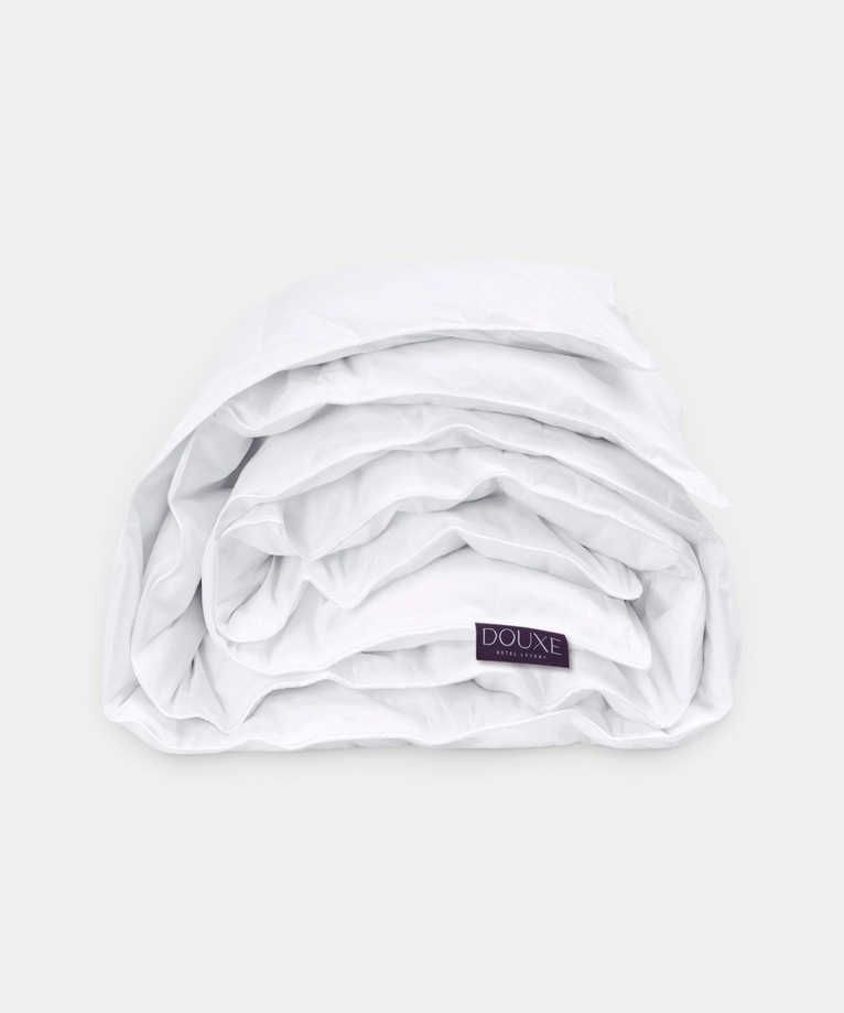 Luxe wit DOUXE dekbed opgevouwen met merklabel zichtbaar